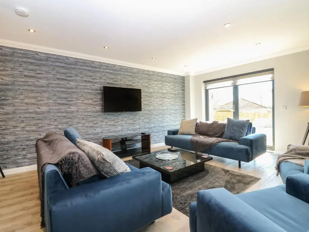 a living room with blue furniture and a brick wall at Woodend Croft in Ellon