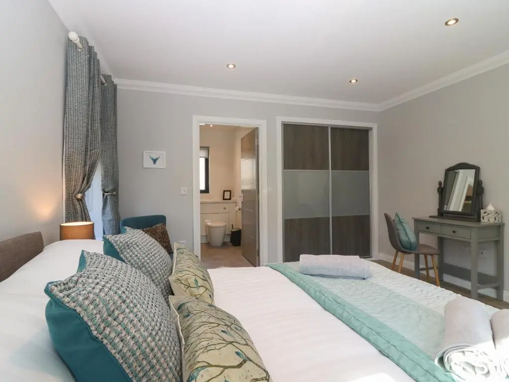a bedroom with a large white bed and a desk at Woodend Croft in Ellon