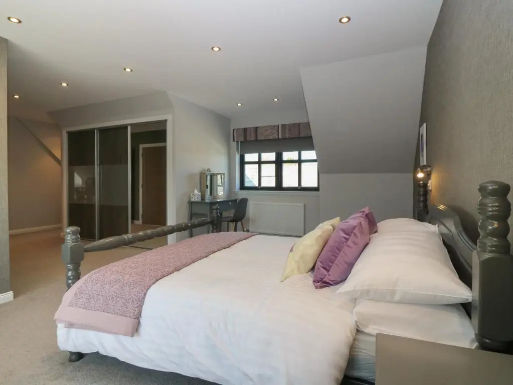 a bedroom with a large bed with purple and white pillows at Woodend Croft in Ellon