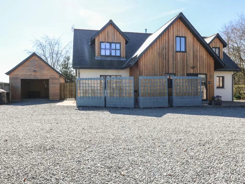 a house with a fence in front of a driveway at Woodend Croft in Ellon