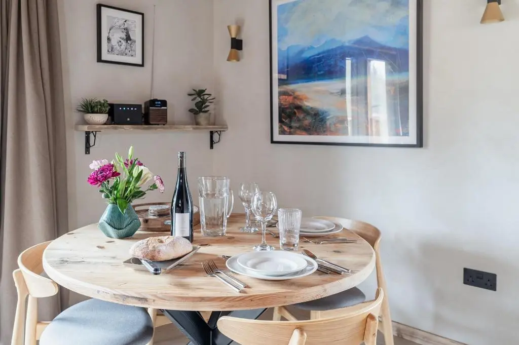 a wooden table with plates and glasses and a bottle of wine at Osprey Lodge in Aviemore