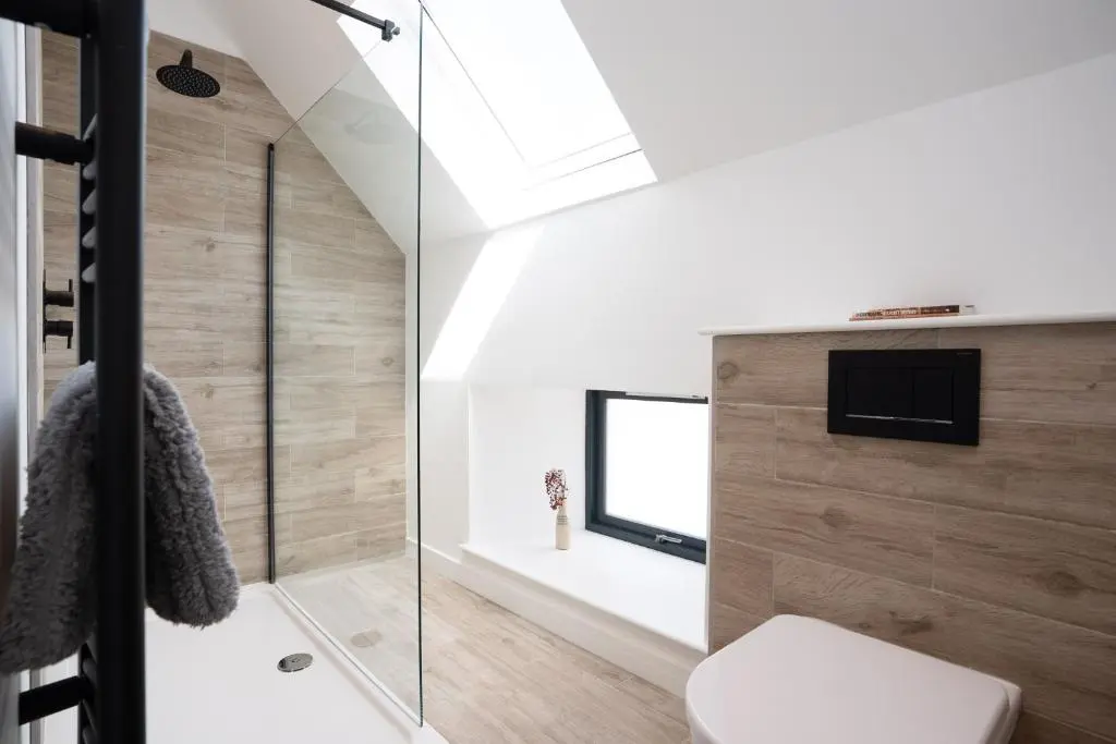 a bathroom with a shower and a toilet and a television at Pityoulish Steading - Seasgair Lodges in Aviemore