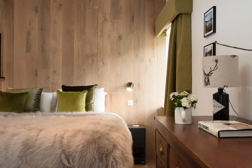 a bedroom with a bed and a table with a lamp at Pityoulish Steading - Seasgair Lodges in Aviemore