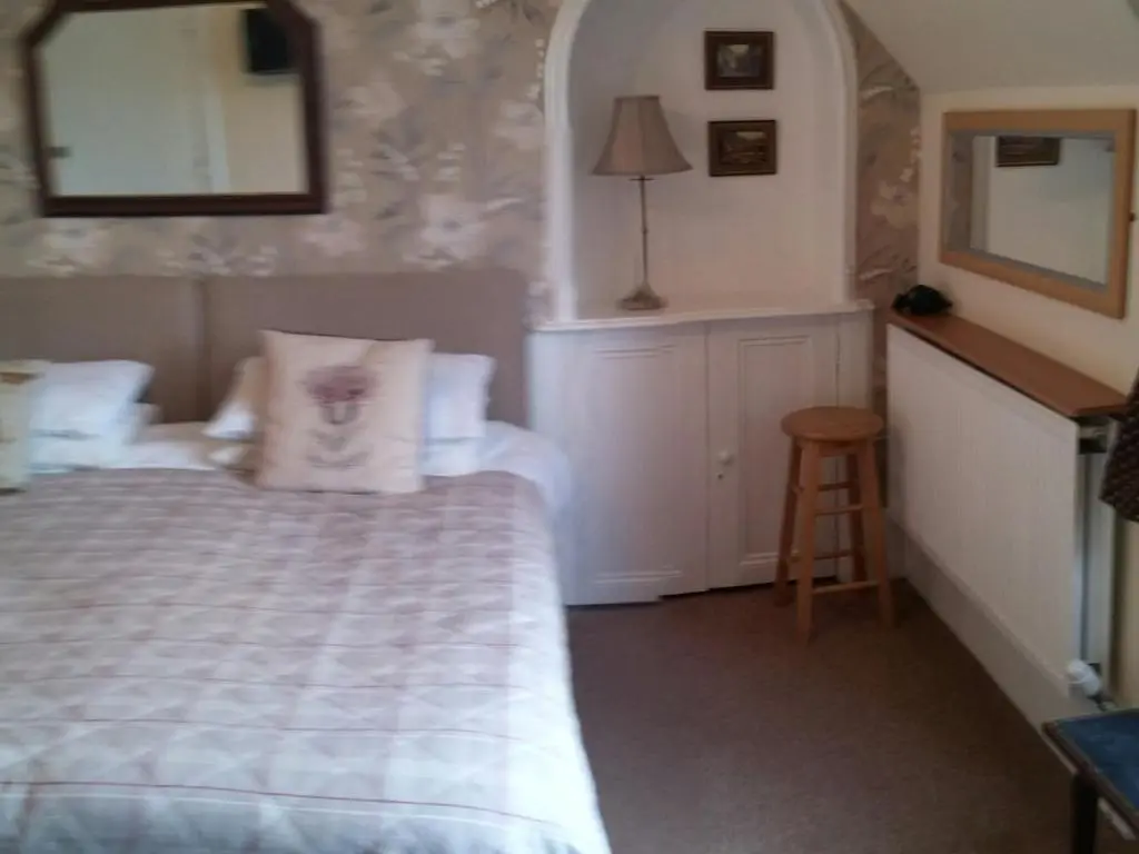a bedroom with a bed and a stool and a mirror at Heathcote B&B in Inverness