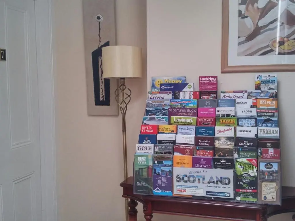 a stack of books on a table next to a lamp at Heathcote B&B in Inverness