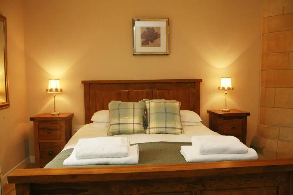 a bedroom with a bed with two pillows and two lamps at Abbey Garden at the Highland Club in Fort Augustus