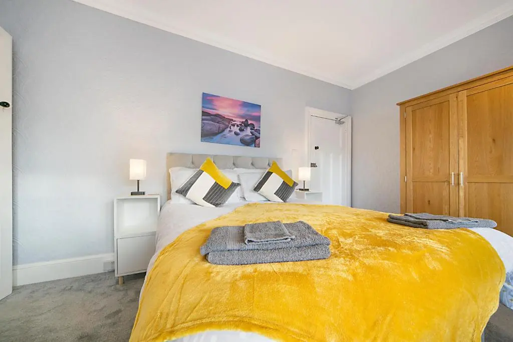 a bedroom with a large bed with a yellow blanket at Constancevilla B8 - Grampian Lettings Ltd in Aberdeen