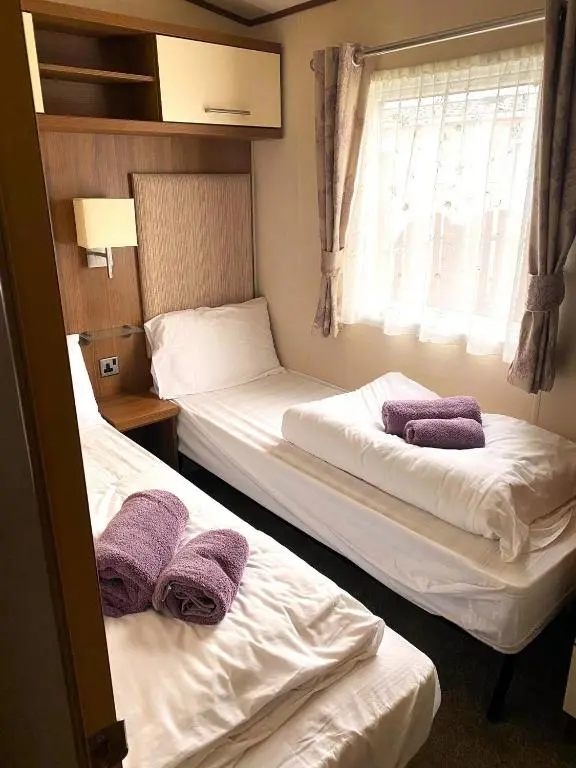 two beds in a room with purple towels on them at Cabin 38 in Aviemore