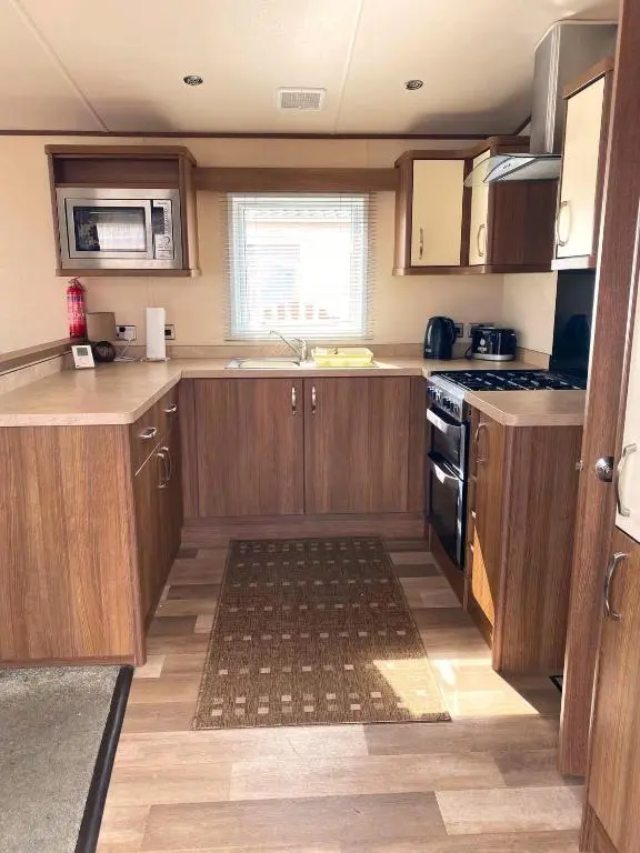 a kitchen with wooden cabinets and a stove top oven at Cabin 38 in Aviemore