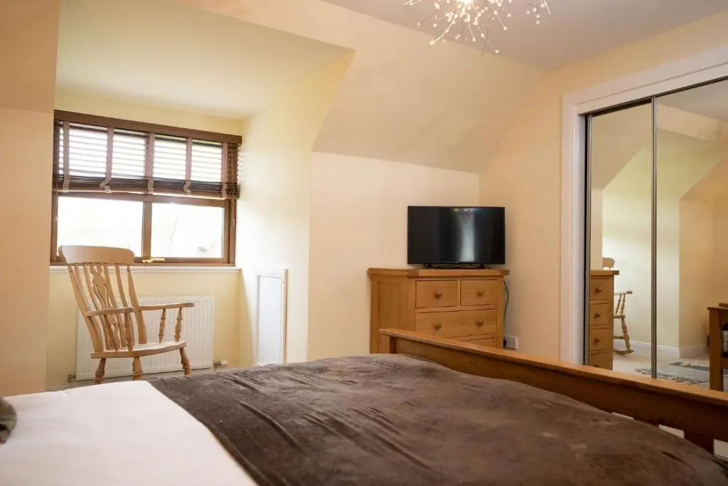 a bedroom with a bed and a tv and a chair at Bracken House in Aviemore
