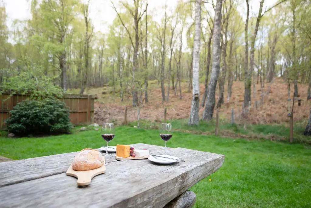a wooden table with two glasses of wine and bread at Bracken House in Aviemore