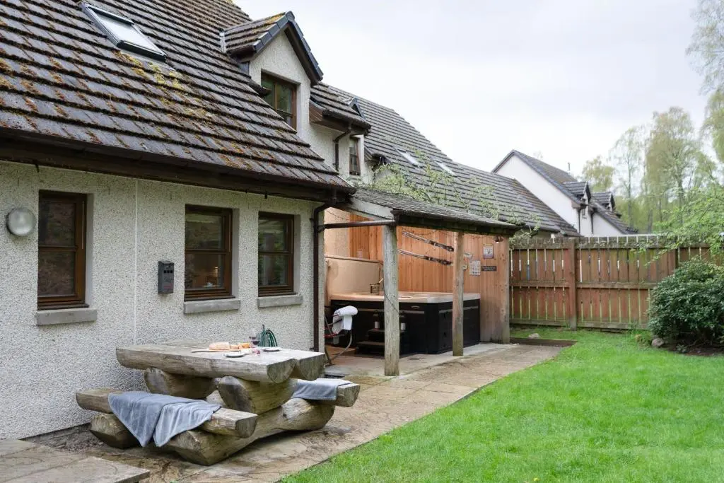 a backyard with a bench and a tub in a yard at Bracken House in Aviemore