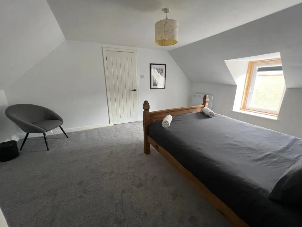 a bedroom with a bed and a chair and a window at MaCaMor in Helmsdale