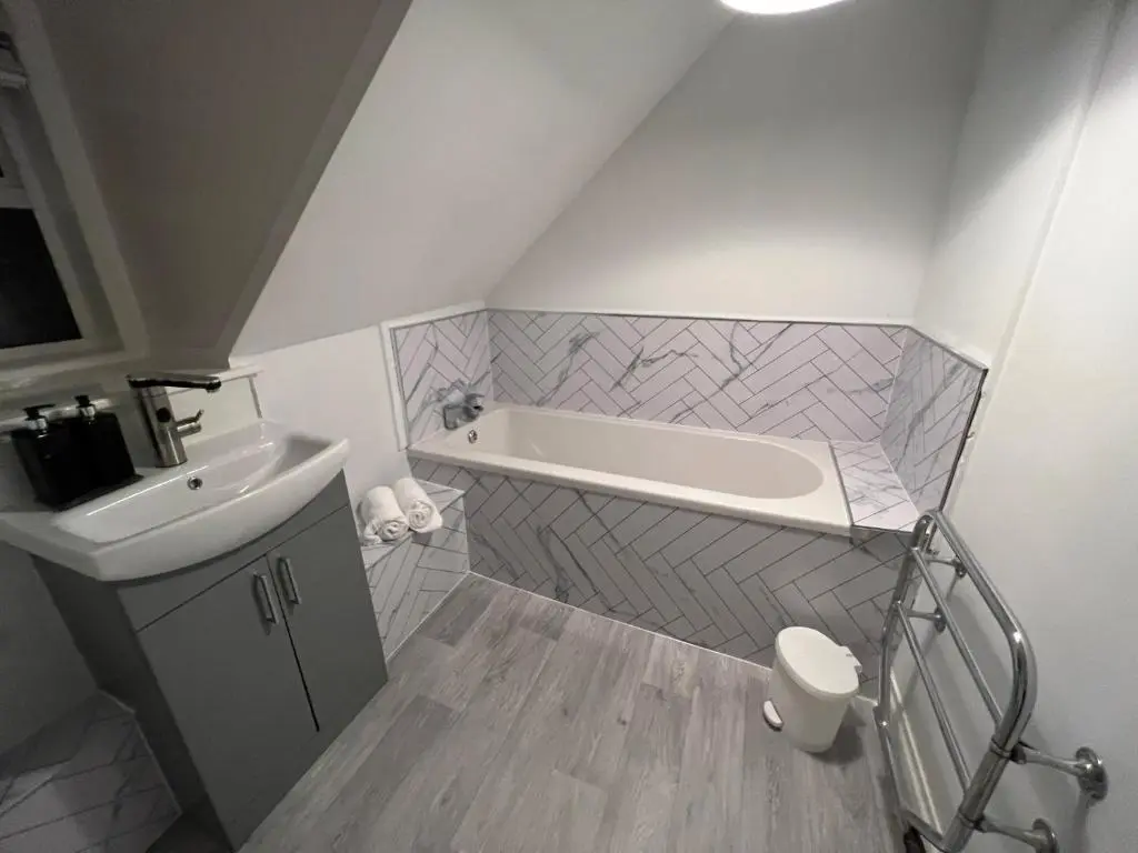 a bathroom with a bath tub and a sink at MaCaMor in Helmsdale