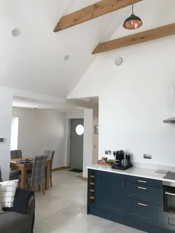 a kitchen and living room with blue cabinets and a table at Nana Cottage , Findhorn Village in Findhorn