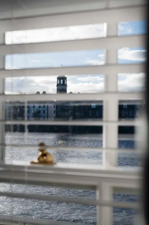 a view of a building with a lighthouse through a window at River View City Centre- Free Parking in Inverness