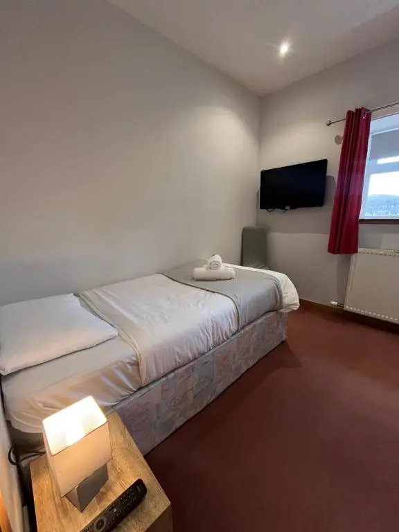 a hotel room with a bed and a television at Columba House in Kingussie