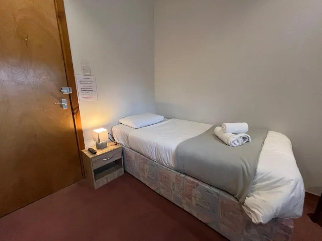 a small bed in a small room with a door at Columba House in Kingussie