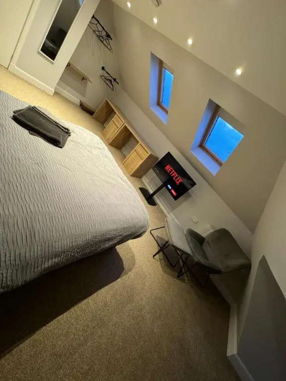 a bedroom with a bed and a desk and windows at Town Centre 2 bedroom apartment in Wick