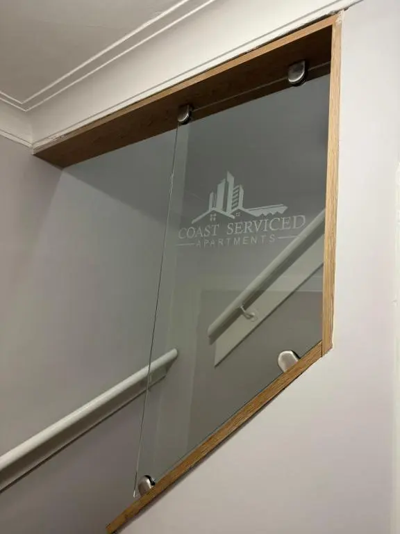 a mirror hanging on a wall with a wood frame at Town Centre 2 bedroom apartment in Wick