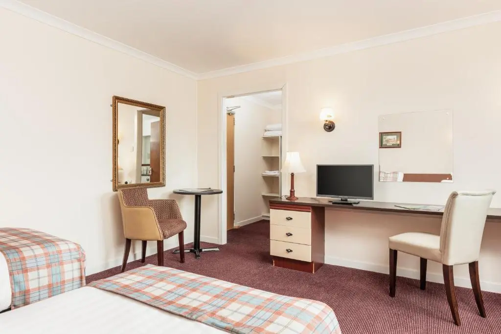 a hotel room with a bed and a desk with a computer at Highlander Hotel \u2018A Bespoke Hotel\u2019 in Newtonmore