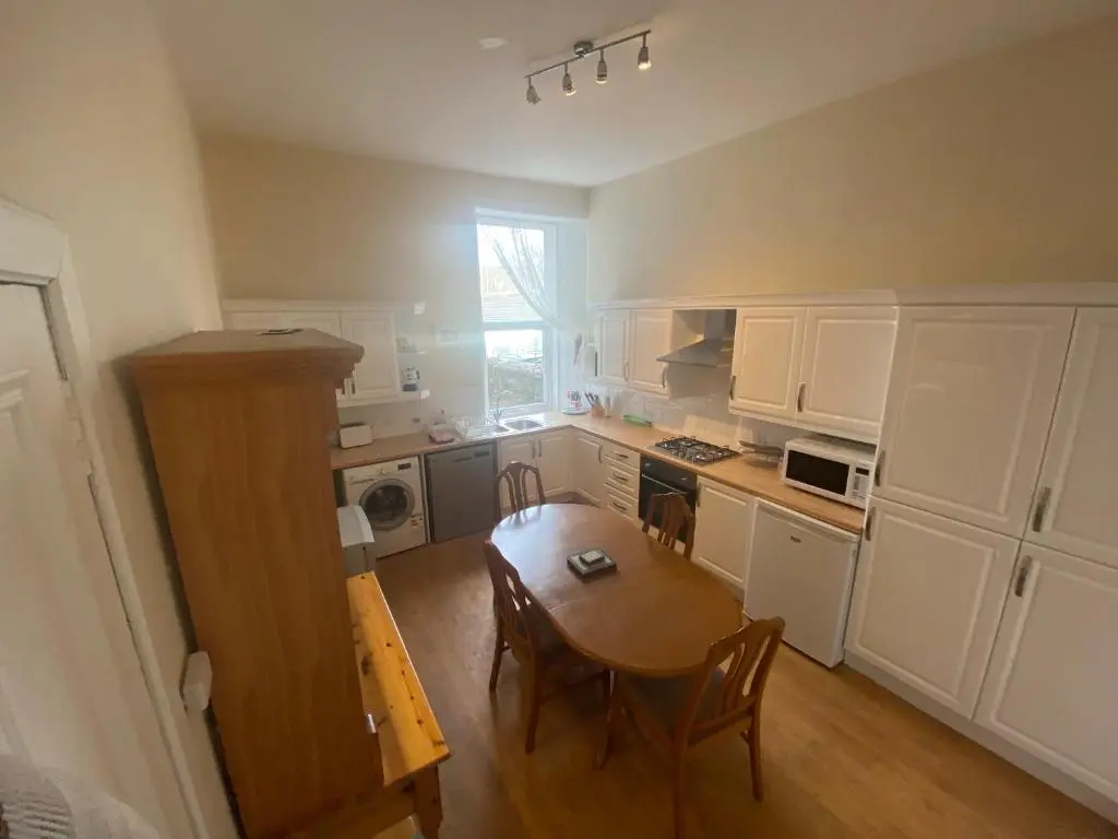 a kitchen with white cabinets and a table and chairs at 92 High Street in Aberlour