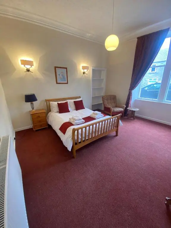 a bedroom with a bed and a chair and a window at 92 High Street in Aberlour