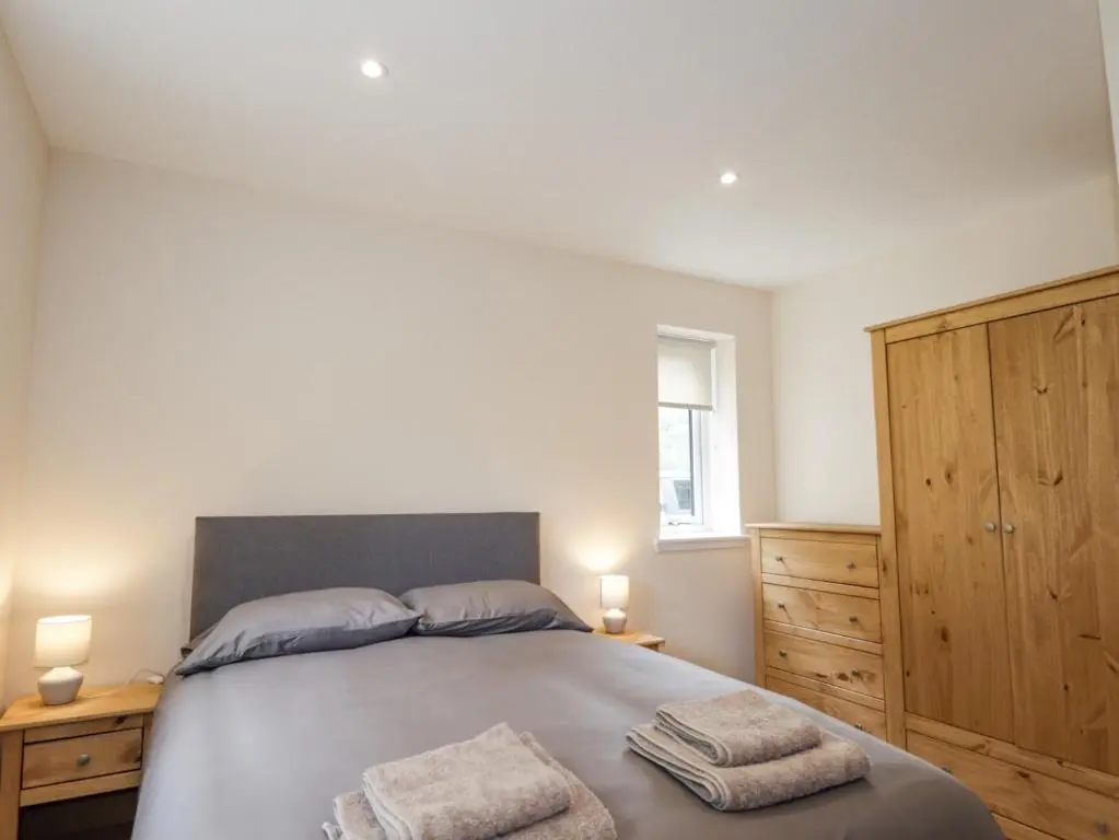 a bedroom with a bed with two towels on it at Crask Bungalow in Beauly