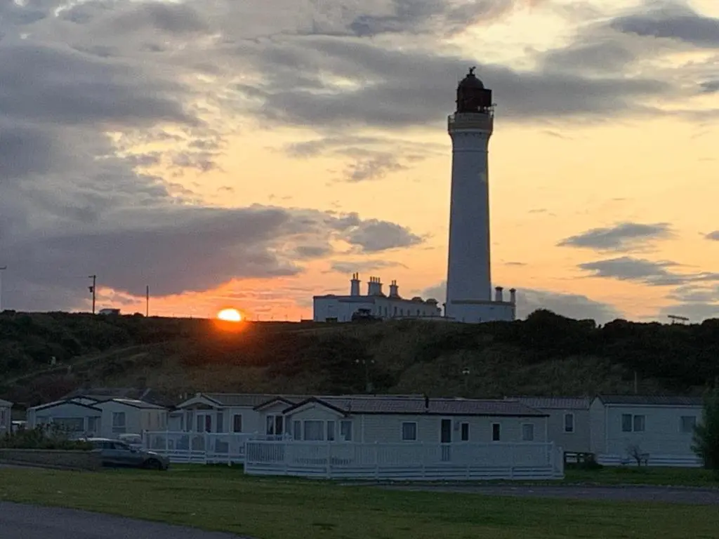 a lighthouse on a hill with the sun setting behind it at Highway in Lossiemouth