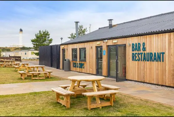 a group of picnic tables in front of a building at Highway in Lossiemouth