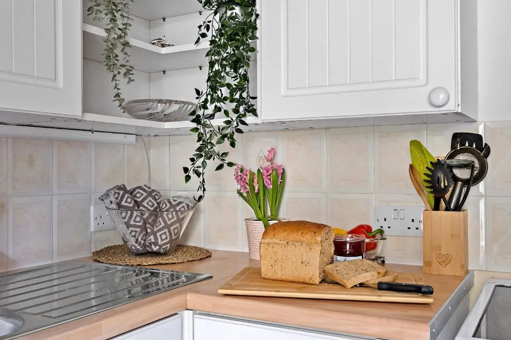 a kitchen counter with a cutting board with bread and flowers at Finest Retreats - The Sea Cottage in Avoch