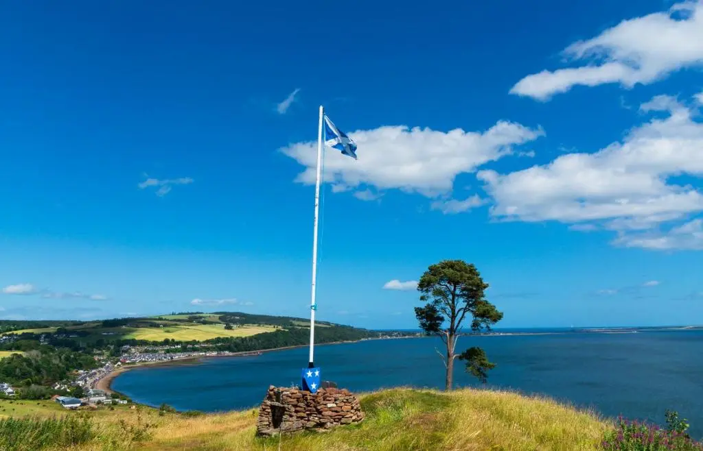 a flag pole on top of a hill with a tree at Finest Retreats - The Sea Cottage in Avoch