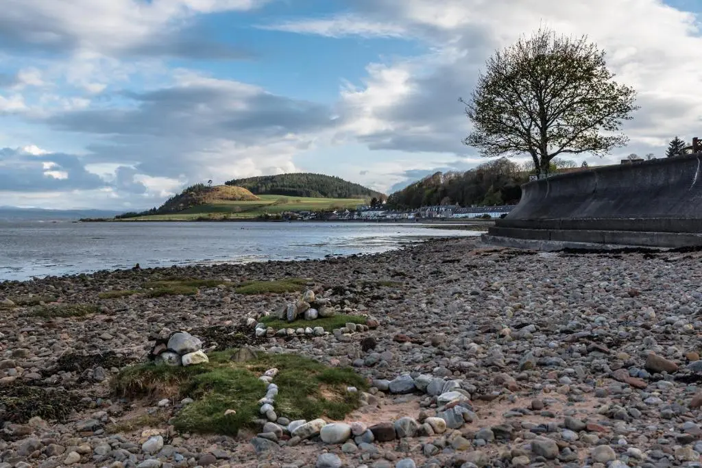 a rocky beach with a tree on the shore at Finest Retreats - The Sea Cottage in Avoch