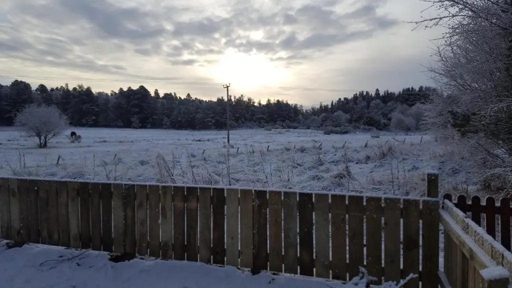 a fence in a snowy field with the sun in the background at Tanleys - Skye Pod in Grantown on Spey