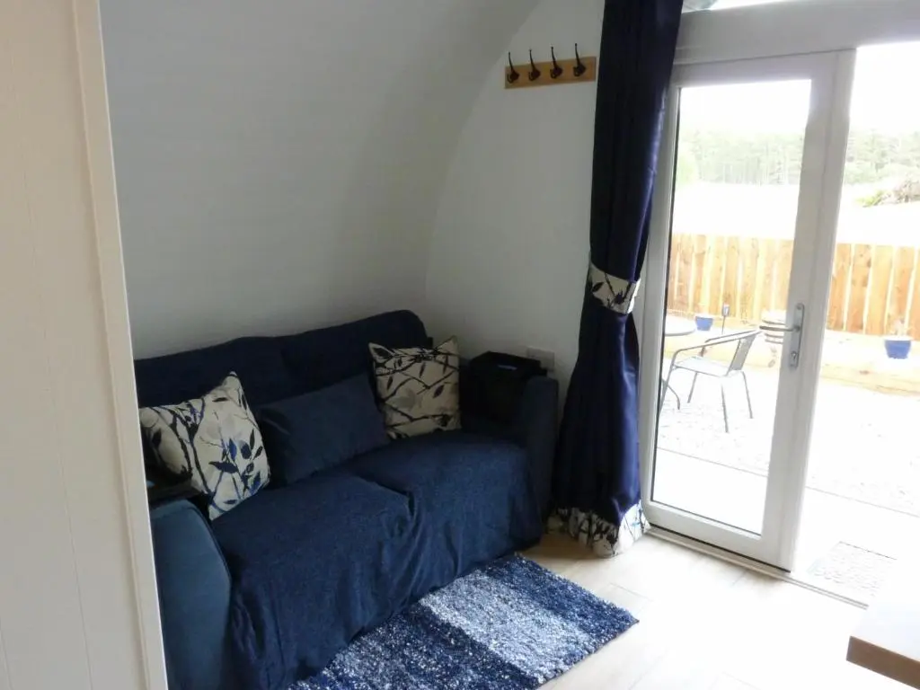 a blue couch in a living room with a sliding glass door at Tanleys - Skye Pod in Grantown on Spey
