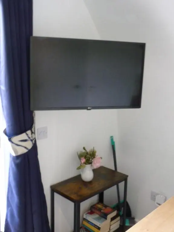 a flat screen tv hanging on a wall with a table at Tanleys - Skye Pod in Grantown on Spey
