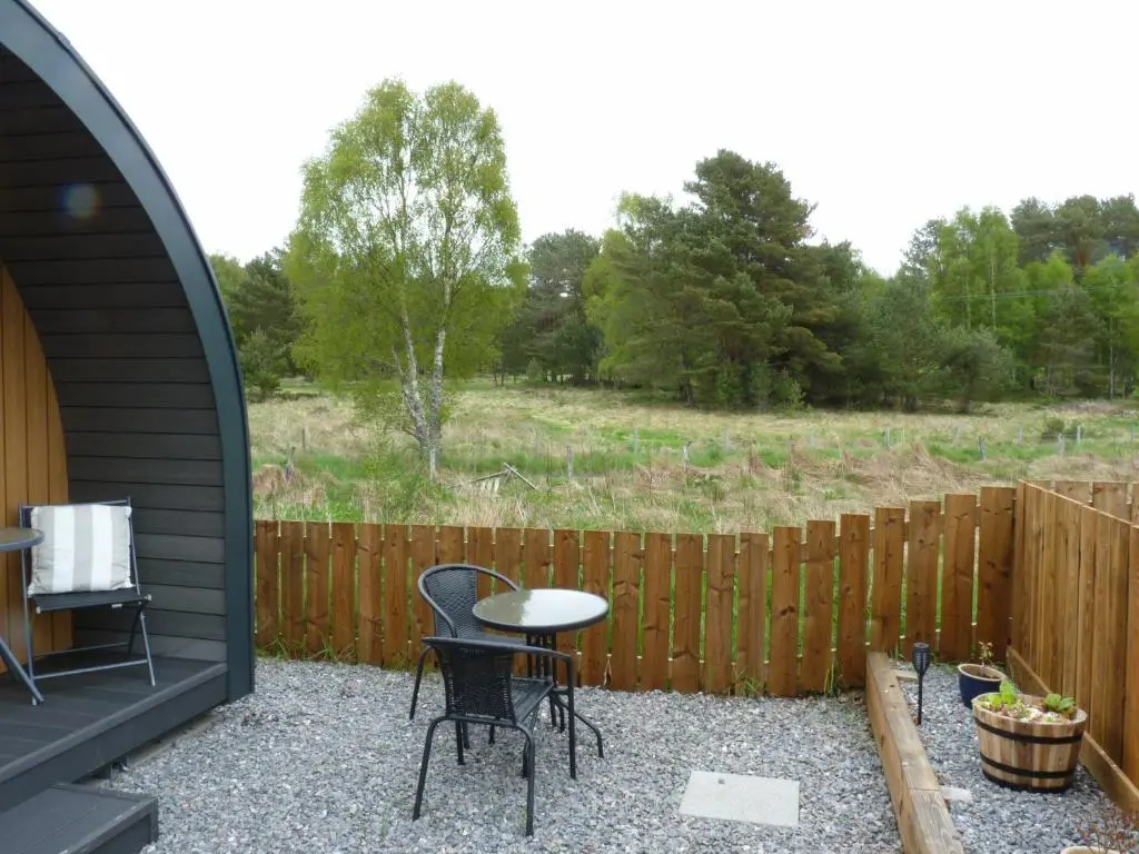a patio with a table and chairs and a fence at Tanleys - Skye Pod in Grantown on Spey
