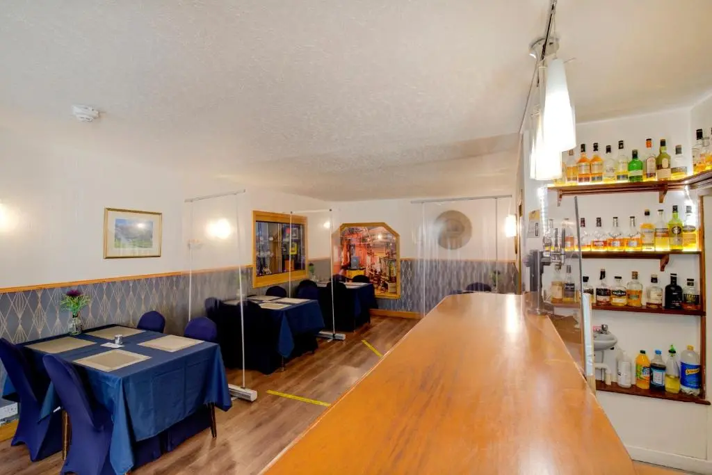 a dining room with two tables and a bar at OYO Eastbank Hotel, Speyside Scotland in Rothes