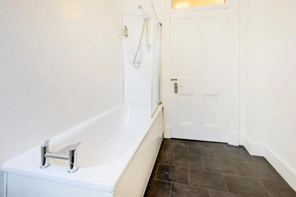 a white bathroom with a shower and a sink at OYO Eastbank Hotel, Speyside Scotland in Rothes