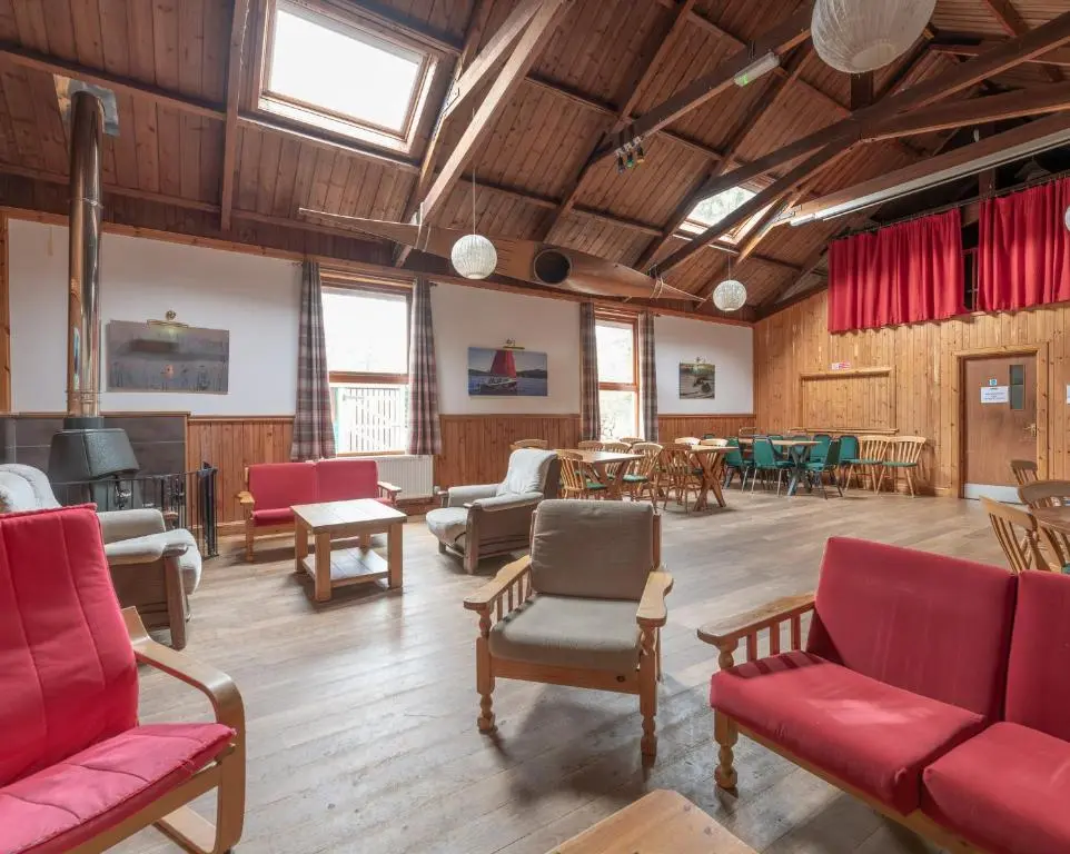 a large room with red chairs and tables at Insh Hall Rooms at Loch Insh in Kincraig