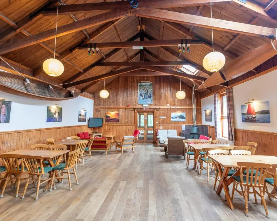 a dining room with tables and chairs and lights at Insh Hall Rooms at Loch Insh in Kincraig