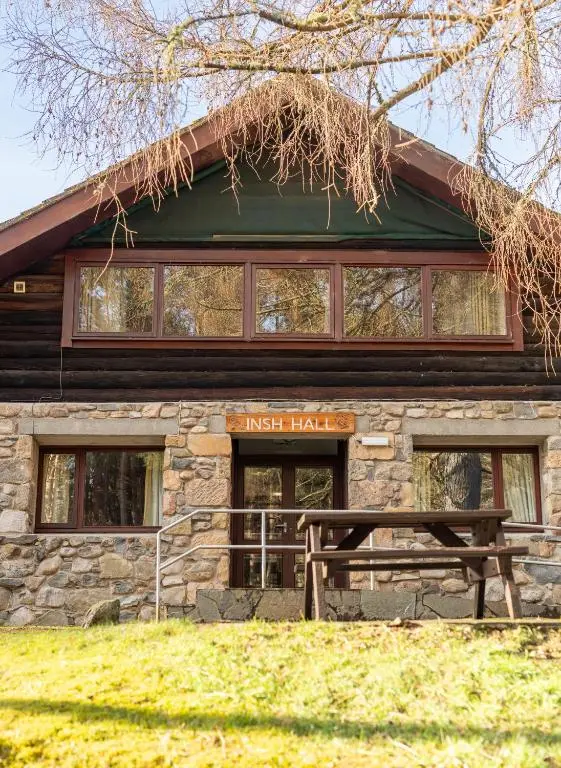 a log cabin with a bench in front of it at Insh Hall Rooms at Loch Insh in Kincraig