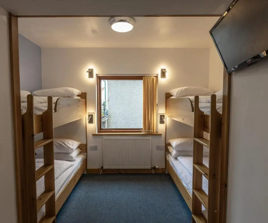 a room with three bunk beds and a window at Insh Hall Rooms at Loch Insh in Kincraig