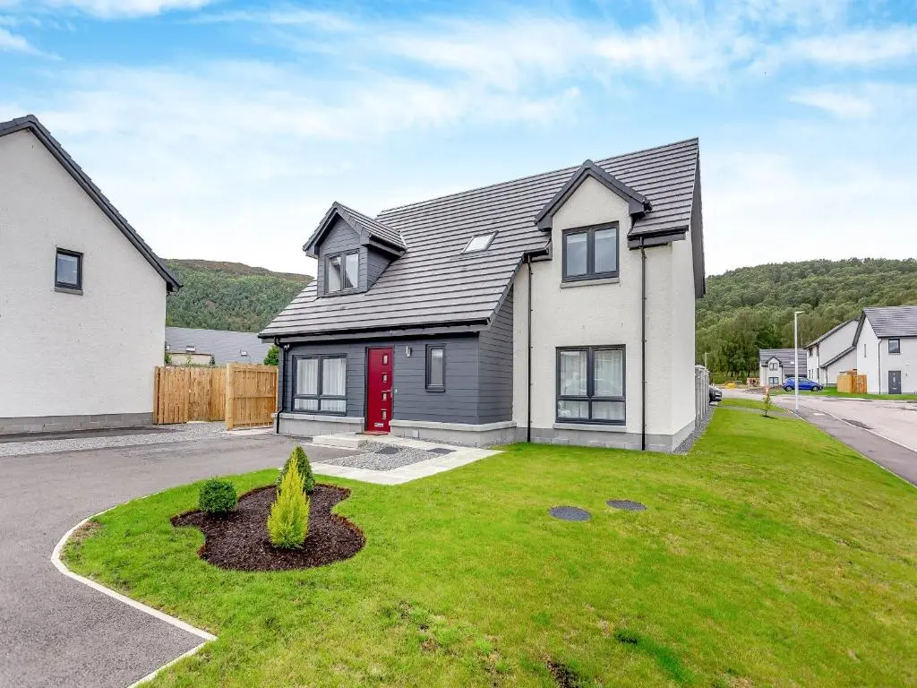 a white house with a red door in a yard at The Beech House in Aviemore