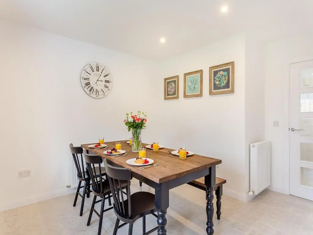 a dining room table with chairs and a clock on the wall at The Beech House in Aviemore