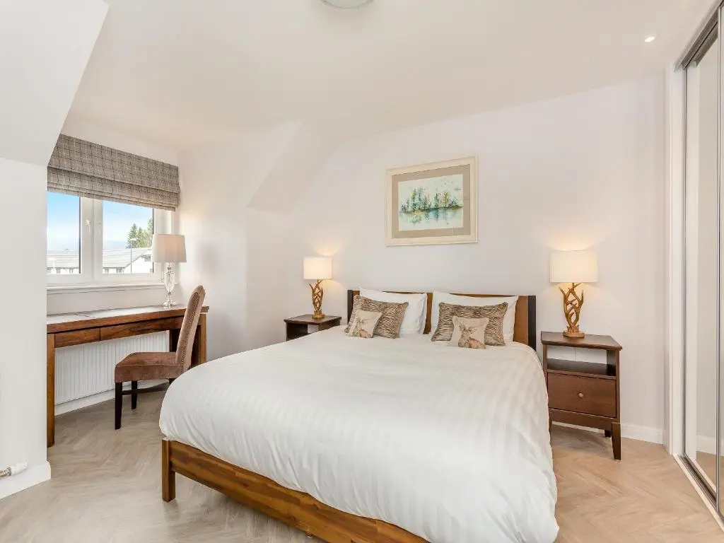 a white bedroom with a bed and a desk at The Beech House in Aviemore