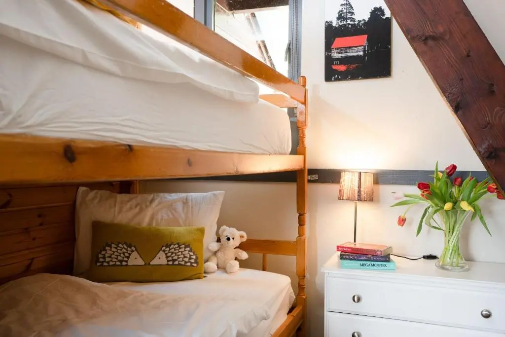 a bedroom with a bunk bed with a teddy bear on a night stand at Wolf Lodge in Carrbridge