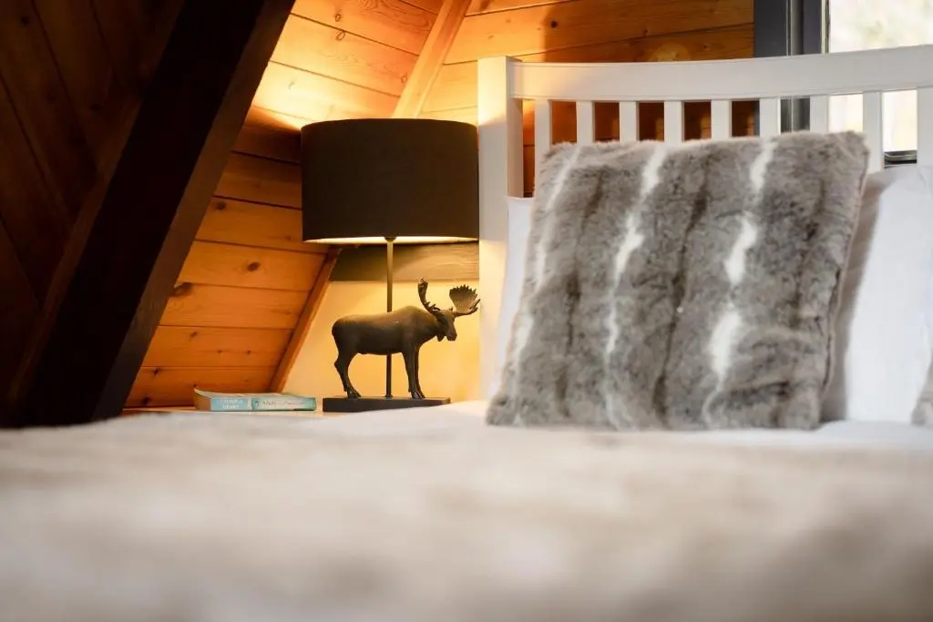 a room with a bed with a lamp and a deer statue at Wolf Lodge in Carrbridge