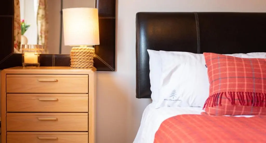 a bedroom with a bed with a lamp and a dresser at Four Pines Lodge in Skye of Curr