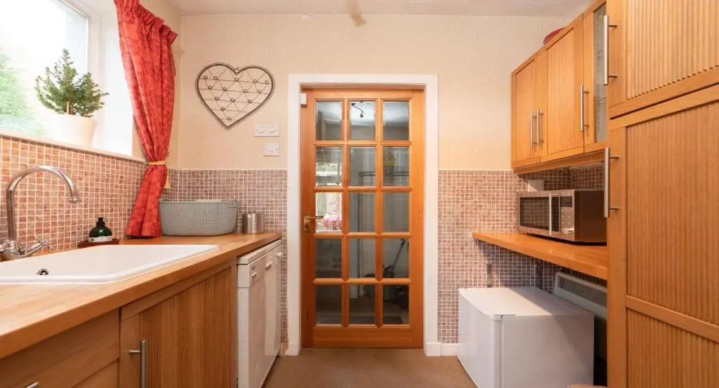 a small kitchen with a sink and a window at Four Pines Lodge in Skye of Curr